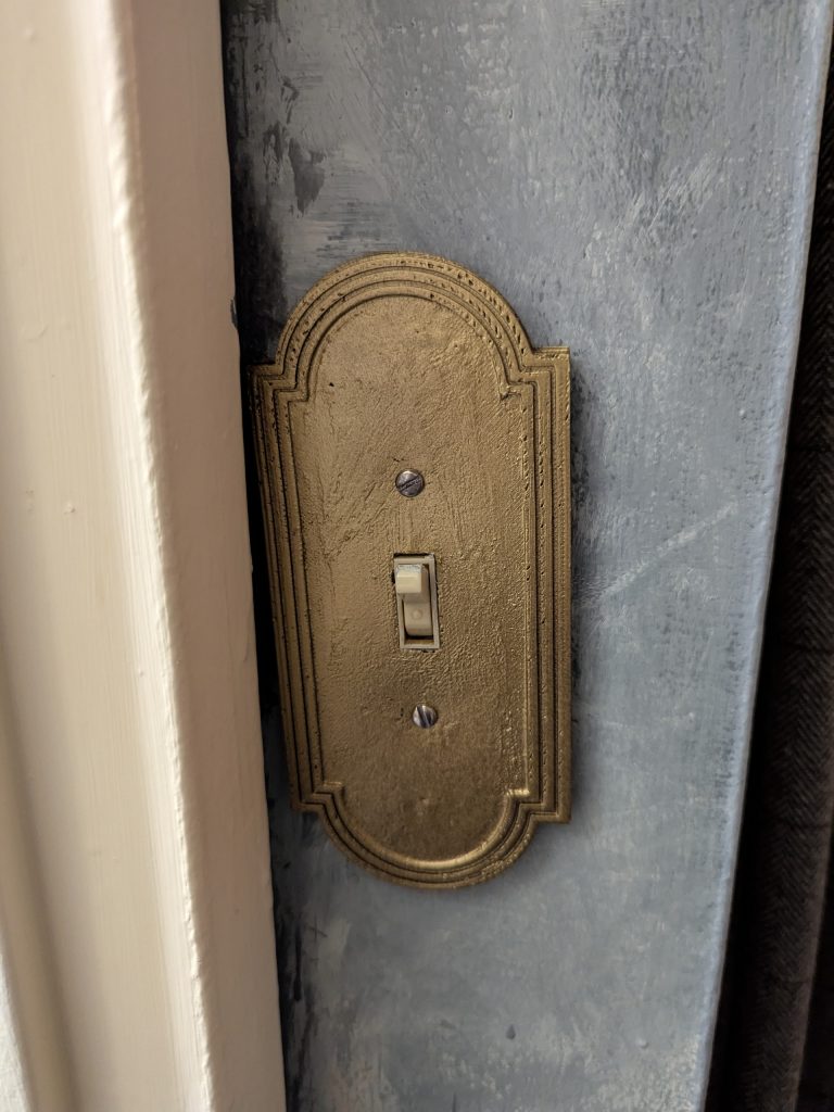 A 3D printed lightswitch plate, spraypainted brass